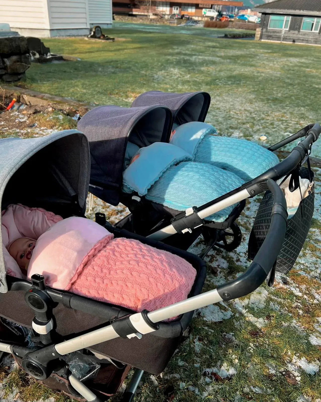 To vogner på en plen med vognposer i rosa og lyseblå kabelstrikk