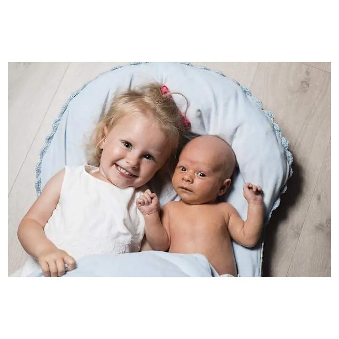 Lite barn og baby ligger sammen på en lyseblå dyne