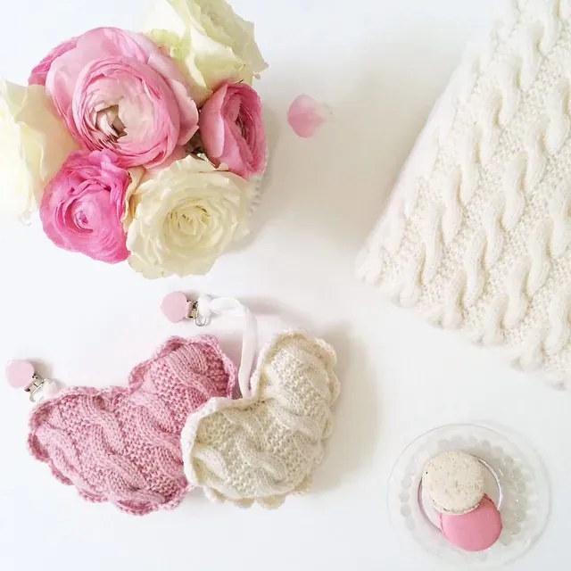 Vognhjerter i rosa og kremhvit kabelstrikk med blomster og en vognpose i kremhvit kabelstrikk