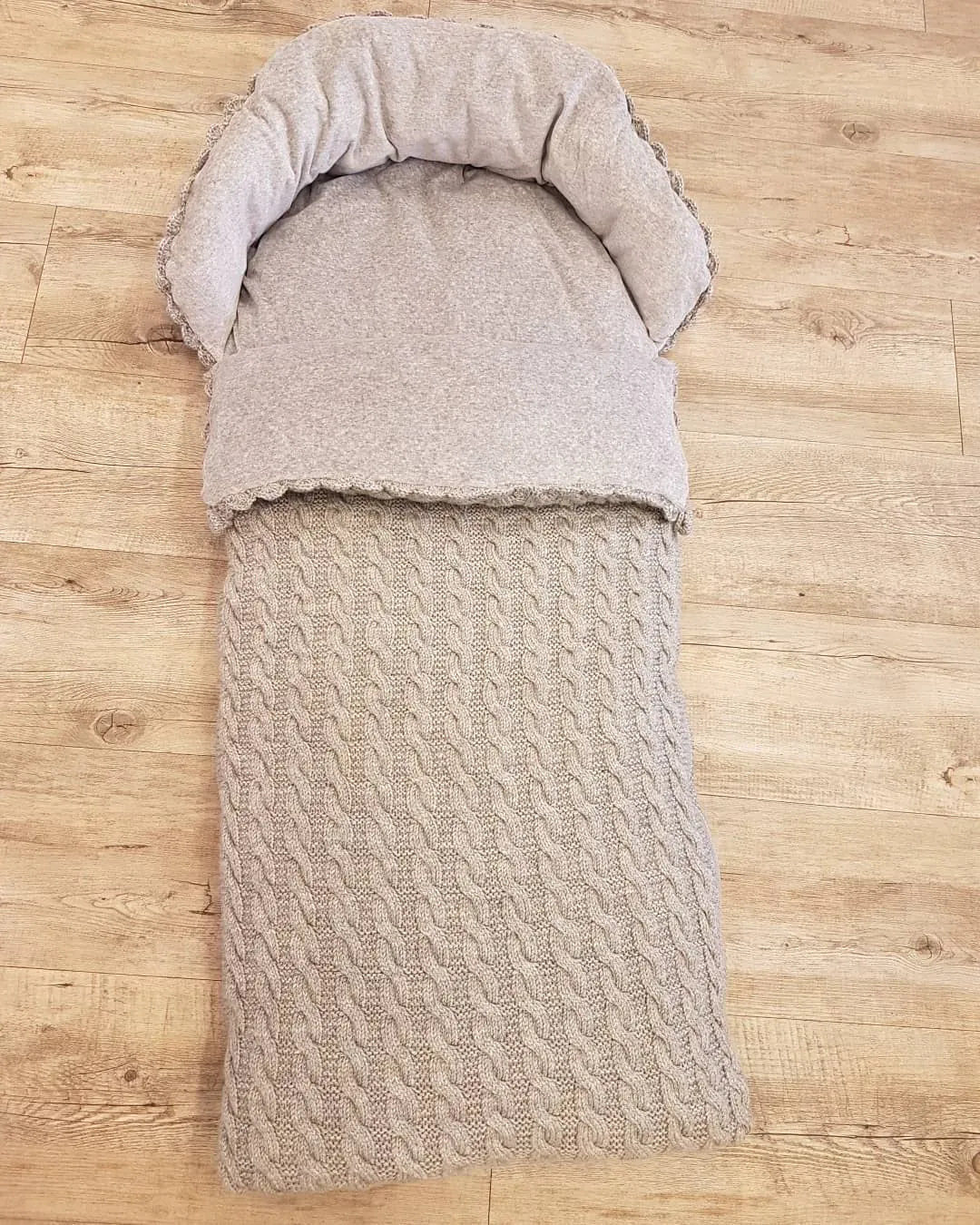 Vognpose i beige kabelstrikk med beige fôr på tregulv, sett ovenfra