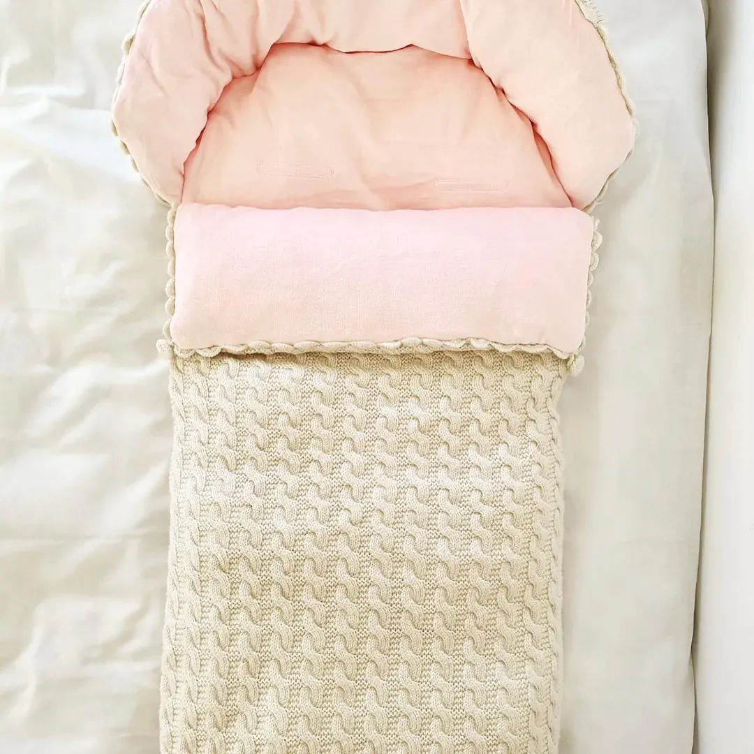 Vognpose i beige kabelstrikk med rosa fôr, sett ovenfra