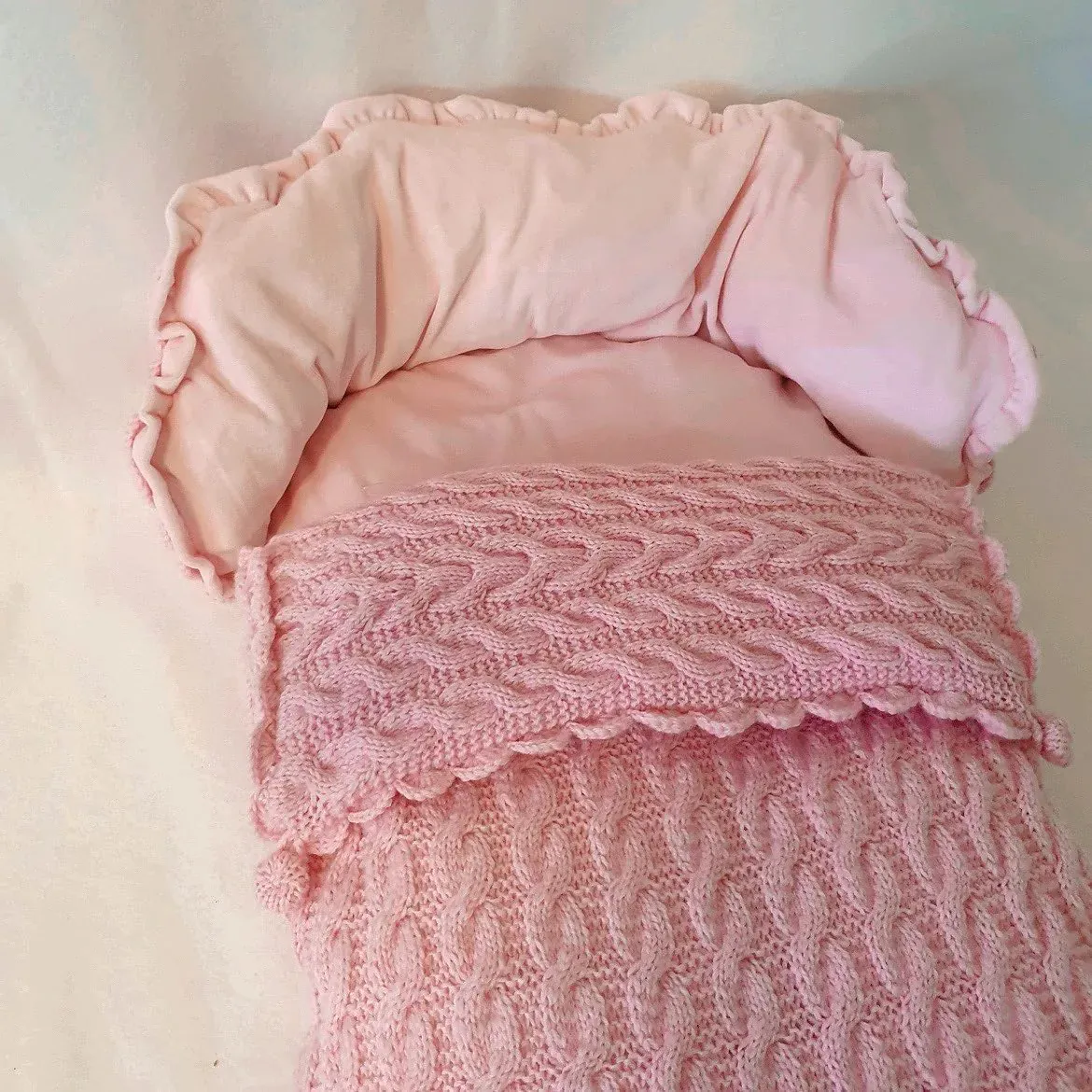Vognpose i rosa kabelstrikk med rosa fôr og rysjekant