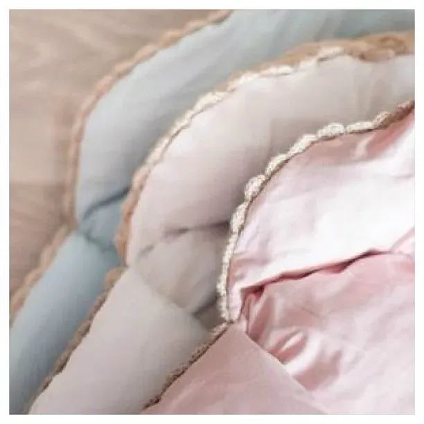 Nærbilde av vognposer med lyseblått og rosa fôr og kant i beige strikk