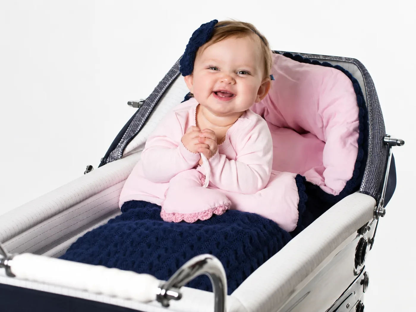 Smilende baby i vogn med marineblå vognpose og rosa fôr